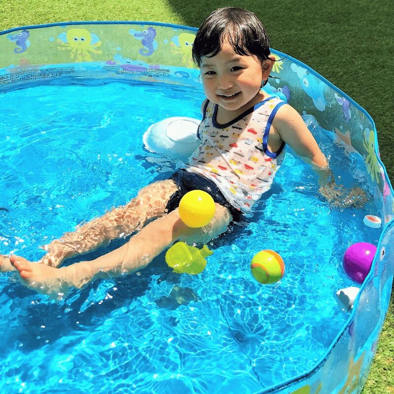 ビニールプールで遊ぶ幼児